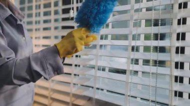 Modern evde mavi bez ve süngerle pencereyi temizleyen adam.