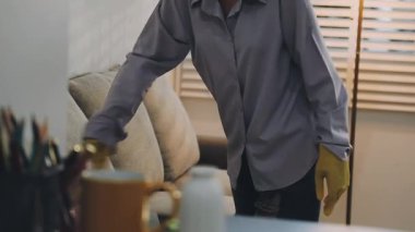 Adam oturma odasını temizliyor.