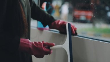 Kadın pencereyi bez ve spreyle temizliyor.