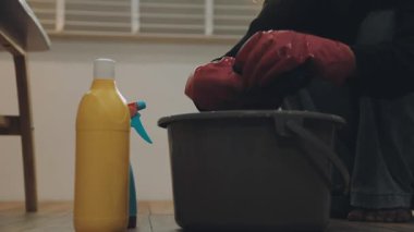 Elinde sarı plastik şişeyle kova tutan bir kadın.