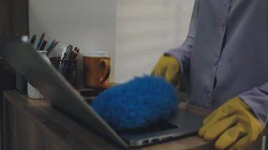 Yakın plan. Ofisi dizüstü bilgisayarla temizleyen adamın fotoğrafı..