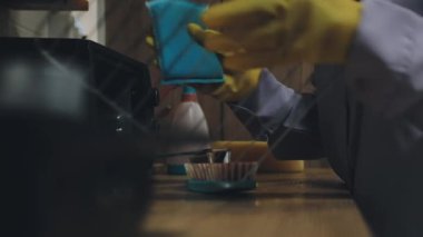 Lastik eldivenli bir adam mutfağı paçavrayla temizliyor.