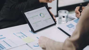 Ofisteki bir tablette mali tabloları tartışan işadamları