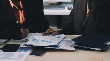 İş adamları ofiste finansal grafikleri tartışıyor ve analiz ediyorlar.