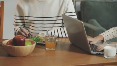 Genç Asyalı kadın modern oturma odasında salata yiyor.