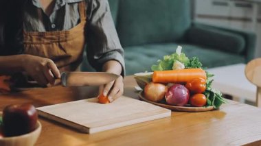 Evdeki mutfakta sebze kesen bir kadın..