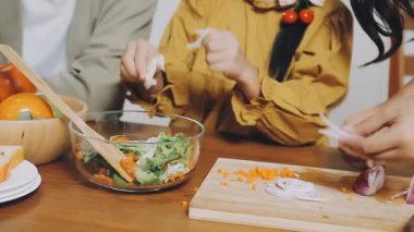 Yakın plan çekimde, genç bir kadın ahşap masa üstünde sebzeli salata yapıyor.