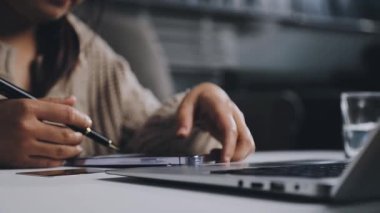 İş kadını dizüstü bilgisayarda çalışıyor ve notlar yazıyor.