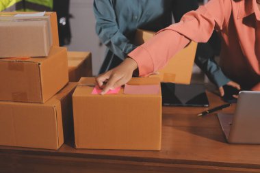 Girişim KOBİ küçük işletme girişimcisi önlük giyen Asyalı kadın dizüstü bilgisayar ve kutu kullanarak çevrimiçi müşterilere, çevrimiçi sme iş fikirlerine satış hazırlamak için siparişleri alır ve gözden geçirir.