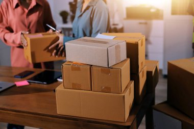 Girişim KOBİ küçük işletme girişimcisi önlük giyen Asyalı kadın dizüstü bilgisayar ve kutu kullanarak çevrimiçi müşterilere, çevrimiçi sme iş fikirlerine satış hazırlamak için siparişleri alır ve gözden geçirir.