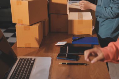 Girişim KOBİ küçük işletme girişimcisi önlük giyen Asyalı kadın dizüstü bilgisayar ve kutu kullanarak çevrimiçi müşterilere, çevrimiçi sme iş fikirlerine satış hazırlamak için siparişleri alır ve gözden geçirir.