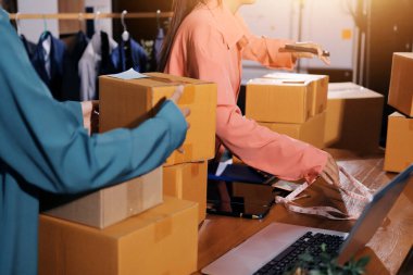 Girişim KOBİ küçük işletme girişimcisi önlük giyen Asyalı kadın dizüstü bilgisayar ve kutu kullanarak çevrimiçi müşterilere, çevrimiçi sme iş fikirlerine satış hazırlamak için siparişleri alır ve gözden geçirir.