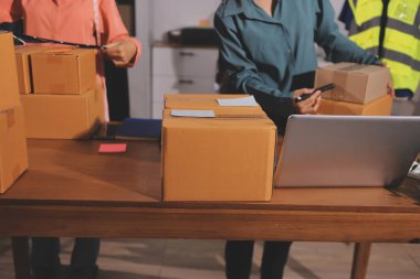 Girişim KOBİ küçük işletme girişimcisi önlük giyen Asyalı kadın dizüstü bilgisayar ve kutu kullanarak çevrimiçi müşterilere, çevrimiçi sme iş fikirlerine satış hazırlamak için siparişleri alır ve gözden geçirir.