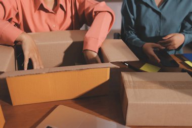 Girişim KOBİ küçük işletme girişimcisi önlük giyen Asyalı kadın dizüstü bilgisayar ve kutu kullanarak çevrimiçi müşterilere, çevrimiçi sme iş fikirlerine satış hazırlamak için siparişleri alır ve gözden geçirir.