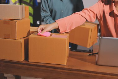 Girişim KOBİ küçük işletme girişimcisi önlük giyen Asyalı kadın dizüstü bilgisayar ve kutu kullanarak çevrimiçi müşterilere, çevrimiçi sme iş fikirlerine satış hazırlamak için siparişleri alır ve gözden geçirir.