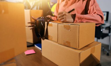 Girişim KOBİ küçük işletme girişimcisi önlük giyen Asyalı kadın dizüstü bilgisayar ve kutu kullanarak çevrimiçi müşterilere, çevrimiçi sme iş fikirlerine satış hazırlamak için siparişleri alır ve gözden geçirir.