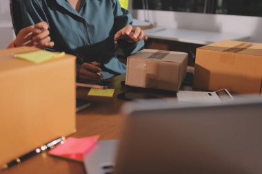 Girişim KOBİ küçük işletme girişimcisi önlük giyen Asyalı kadın dizüstü bilgisayar ve kutu kullanarak çevrimiçi müşterilere, çevrimiçi sme iş fikirlerine satış hazırlamak için siparişleri alır ve gözden geçirir.