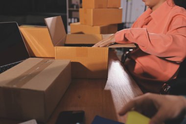 Girişim KOBİ küçük işletme girişimcisi önlük giyen Asyalı kadın dizüstü bilgisayar ve kutu kullanarak çevrimiçi müşterilere, çevrimiçi sme iş fikirlerine satış hazırlamak için siparişleri alır ve gözden geçirir.