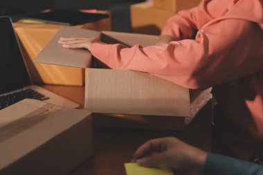 Girişim KOBİ küçük işletme girişimcisi önlük giyen Asyalı kadın dizüstü bilgisayar ve kutu kullanarak çevrimiçi müşterilere, çevrimiçi sme iş fikirlerine satış hazırlamak için siparişleri alır ve gözden geçirir.