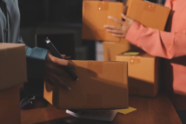 Girişim KOBİ küçük işletme girişimcisi önlük giyen Asyalı kadın dizüstü bilgisayar ve kutu kullanarak çevrimiçi müşterilere, çevrimiçi sme iş fikirlerine satış hazırlamak için siparişleri alır ve gözden geçirir.