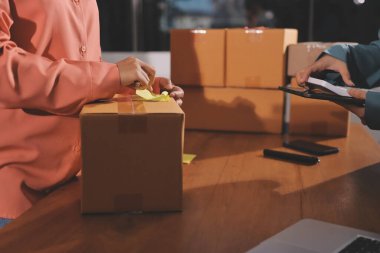 Girişim KOBİ küçük işletme girişimcisi önlük giyen Asyalı kadın dizüstü bilgisayar ve kutu kullanarak çevrimiçi müşterilere, çevrimiçi sme iş fikirlerine satış hazırlamak için siparişleri alır ve gözden geçirir.