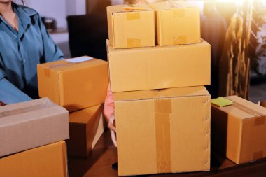 Girişim KOBİ küçük işletme girişimcisi önlük giyen Asyalı kadın dizüstü bilgisayar ve kutu kullanarak çevrimiçi müşterilere, çevrimiçi sme iş fikirlerine satış hazırlamak için siparişleri alır ve gözden geçirir.