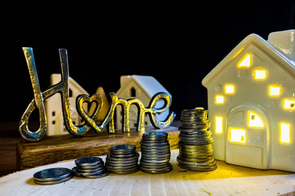 home price increase concept illustration metal home sign with coins and ceramic houses with light buying house from an agent