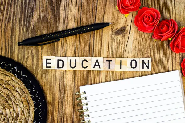 Education flat lay scattered letters with notebook and pen and straw mat and roses