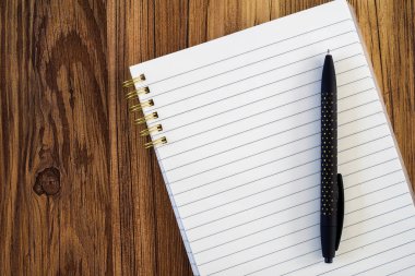 boş not defteri ahşap arka planda siyah kalemle modellenir.