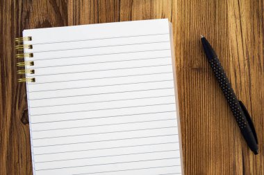 boş not defteri ahşap arka planda siyah kalemle modellenir.