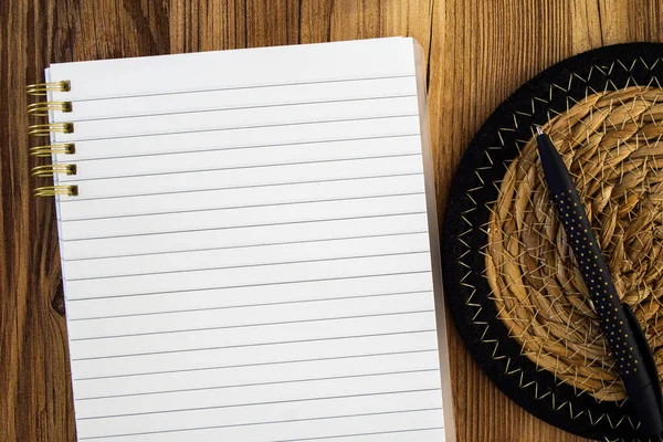 lined blank note pad mock up with a black pen on a straw mat
