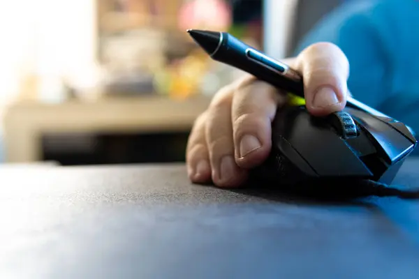 white person with a stylus in hand using a mouse