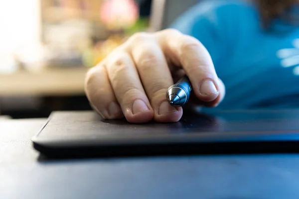 white person holding a stylus pen on a graphic tablet