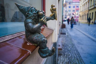 Wrocaw, Polonya - 08 Aralık 2023: Cüce adı Bartonik, pencerenin önünde oturuyor ve Iconic Wrocaw Cüceleri yiyor.