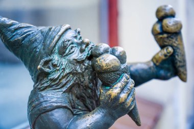 Wrocaw, Polonya - 08 Aralık 2023: Cüce adı Bartonik, pencerenin önünde oturuyor ve Iconic Wrocaw Cüceleri yiyor.