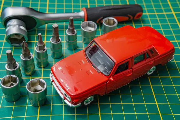 Toy car on grid pattern with screwdriver and bits self repair used car maintenance concept car self service