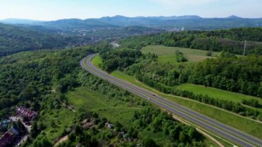 Tepe manzaralı bir otobana doğru uçarken arka planda bir şehir var.