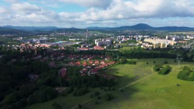 Polonya, Walbrzych 'e doğru uçuyor, şehirlerdeki yerleşim yerleri, yemyeşil ağaçların arasında kümelenmiş evler, engebeli tepeler ve uçsuz bucaksız yeşil ormanlar arasında yuva yapmış bir şehrin havadan manzarası.