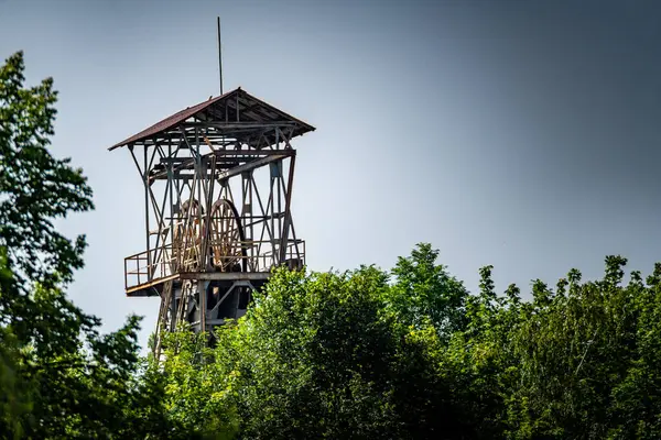 stock image A Rusted Mining Headframe Towering Over Lush Foliage