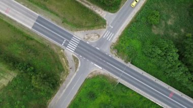 Kavşaktaki Sarı bir arabanın gündüz çevresi yeşilliklerle çevrili havadan görüntüsü