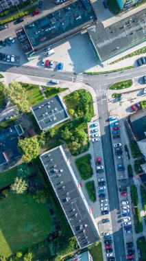 Kalabalık bir kavşağın havadan görüntüsü. Gün ışığında birden fazla park edilmiş araba ve yeşil peyzaj var.