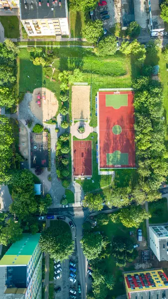 Canlı bir topluluk spor kompleksinin havadan görünüşü. Oyun alanları ve bahçeleri yerleşim alanlarında yeşilliklerle çevrili.