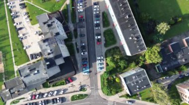 Gündüz saatlerinde binalar ve yeşil alanlarla çevrili işlek bir şehir otoparkının havadan görüntüsü