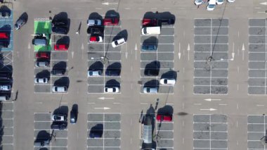 Neredeyse boş bir otoparkın havadan görüntüsü. Gün ortasında bir banliyö alışveriş merkezinde dağınık araçlarla.