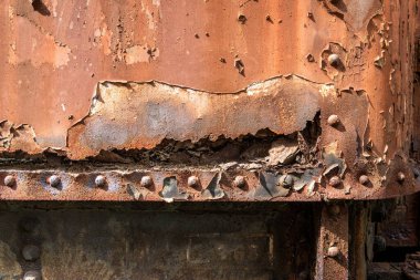 Paslı bir buharlı trenin detayları yıpranmış metal, soyulmuş boya ve aşınmış perçin arka plan dokusu.