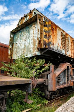 İhmal edilmiş bir tren istasyonunda yeşilliklerle çevrili eski paslı bir buhar treninin detayları.