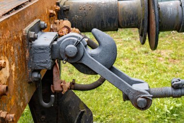 Yeşil bir alanda eski paslı bir buhar treni bağlantı mekanizmasının detaylı görüntüsü