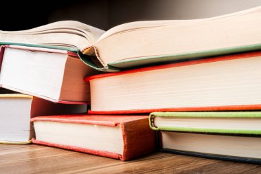 Ahşap bir yüzeye yığılmış eğitici kitaplar. Güneş ışığı renkli dikenlerini aydınlatıyor.