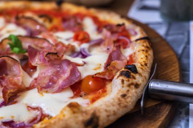 Akşam sıcak bir restoranda peynirli ve kiraz domatesli nefis jambonlu pizza.