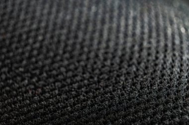 Örülmüş ayakkabı yüzeyinin yakın plan detayı koyu bir arkaplana ayarlanmış ve eşsiz dokumasını vurguluyor